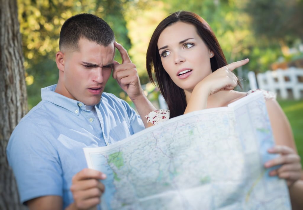 Lost and Confused Mixed Race Couple Looking Over A Map Outside Together.